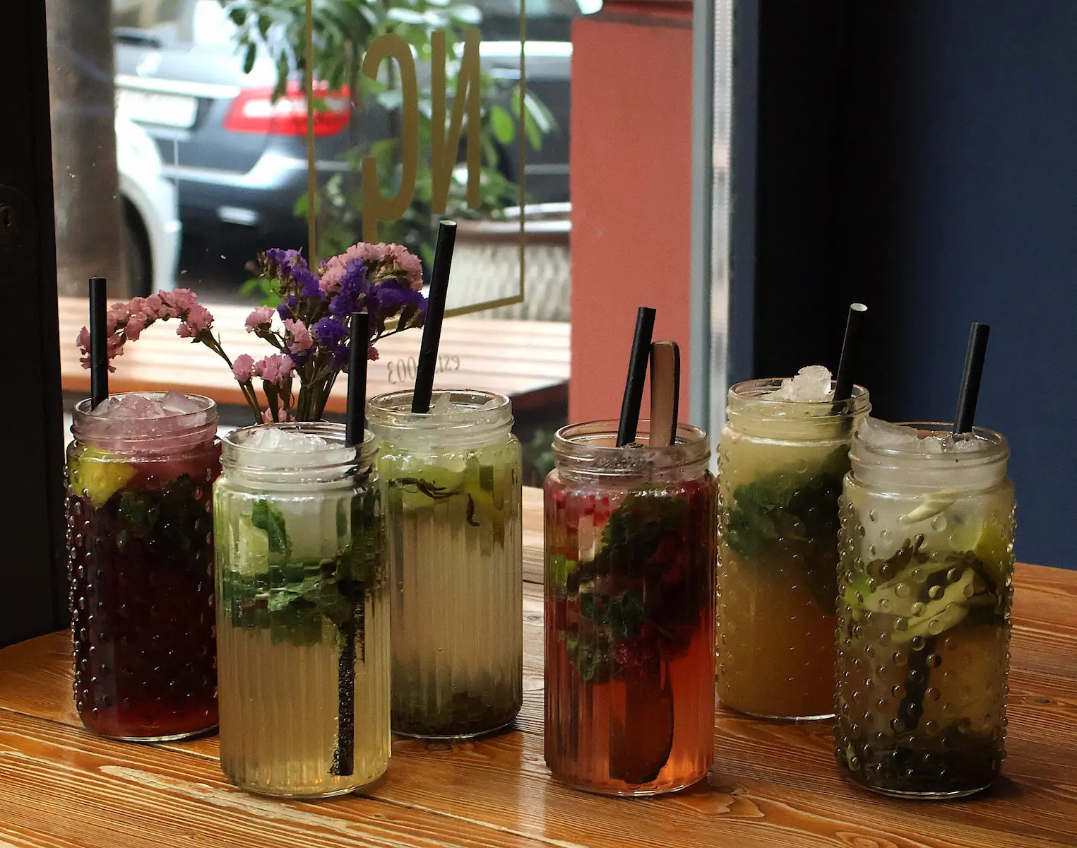 Erfrischende hausgemachte Limonaden mit Beeren und Minze am Fenster serviert